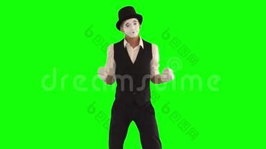 穿着黑白衣服模仿舞蹈的滑稽男哑剧演员。一个演员在绿色背景下表演节目。色度